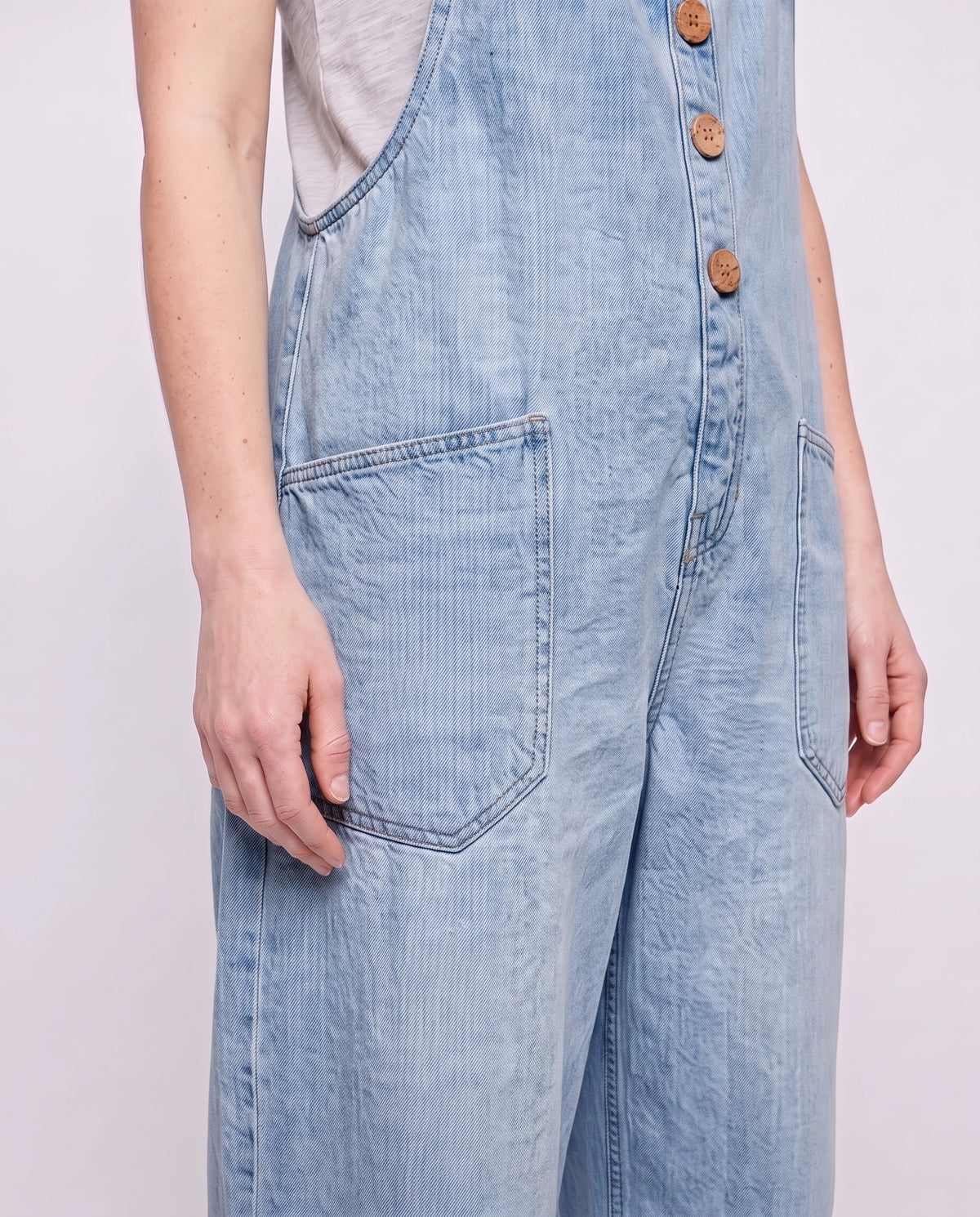 Salopette femme ample effet denim La Tournée, coloris bleu clair, détail des bretelles à œillets et de la bavette boutonnée