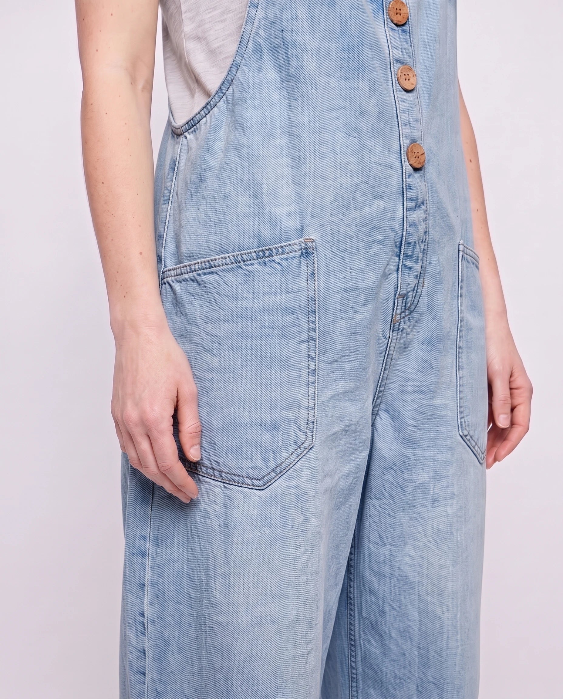 Salopette femme ample effet denim La Tournée, coloris bleu clair, détail des bretelles à œillets et de la bavette boutonnée